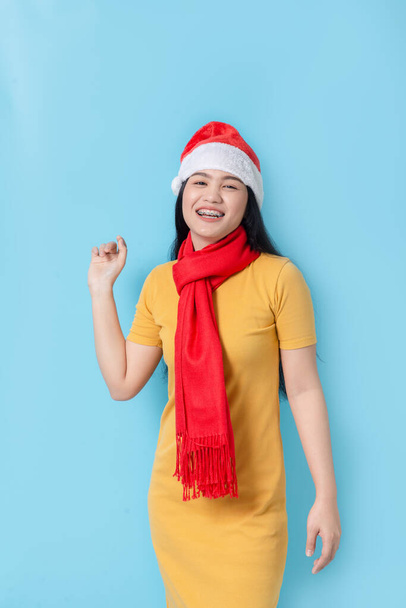 Azjatka w żółtej sukience z czerwonym szalikiem i kapeluszem Mikołaja, hol - Zdjęcie, obraz