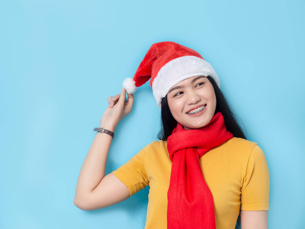 Asian woman in yellow dress wearing red scarf and Santa hat, hol - 写真・画像
