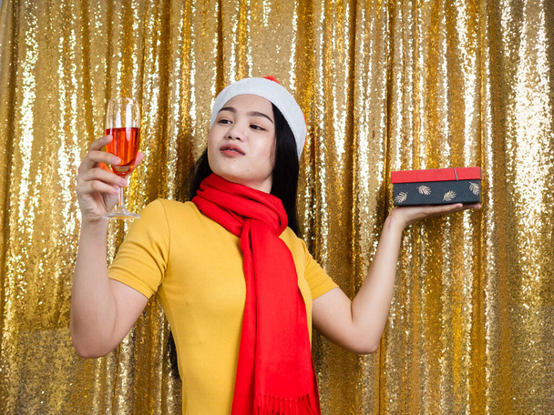 Happy Asian woman with red Santa hat and drinking red wine on go - Fotoğraf, Görsel