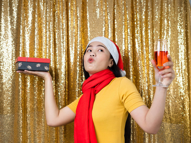 Happy Asian woman with red Santa hat and drinking red wine on go - Фото, зображення