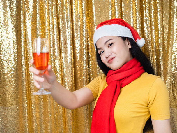 Happy Asian woman with red Santa hat and drinking red wine on go - Foto, Bild