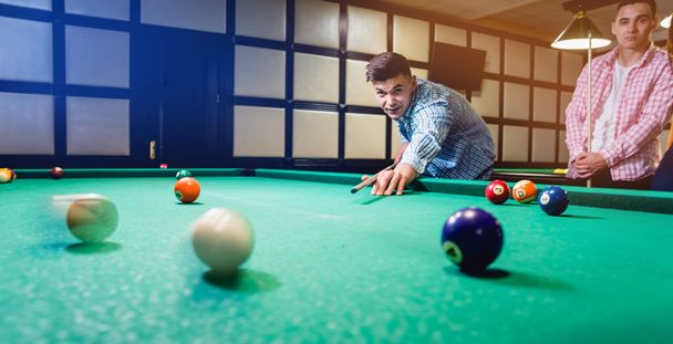 Young man trying to hit the ball in billiard. Pool background - Фото, изображение