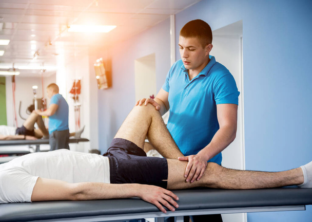 Rehabilitation therapy. Physiotherapist working with young male patient in the rehabilitation center - Photo, image