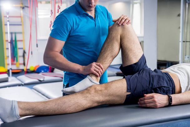 Rehabilitation therapy. Physiotherapist working with young male patient in the rehabilitation center - Foto, Bild