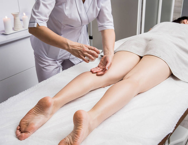 Beautiful young woman enjoying legs massage in spa salon. Cosmetology concept - Photo, image