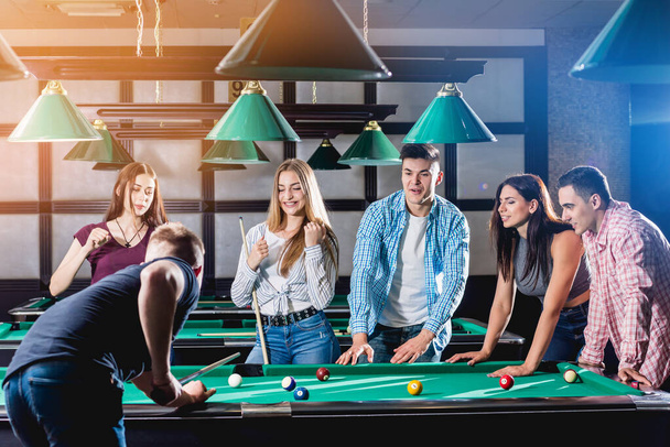Group of young cheerful friends playing billiards. Funny time after work - Zdjęcie, obraz