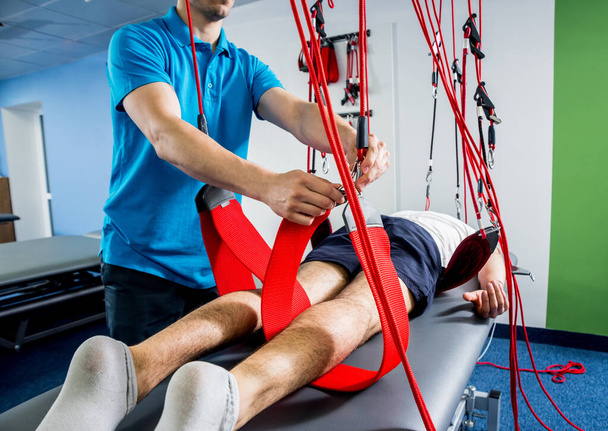 Physiotherapy. Suspension training therapy. Young man doing fitness traction therapy with suspension-based exercise training system. Treatment of pain in the spine. - Fotoğraf, Görsel