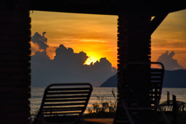erstaunliche, wunderbare und dramatische goldfarbene Himmel hinter den Wolken während eines atemberaubenden Sonnenuntergangs an einem magischen Strand der Insel Langkawi in Malaysia - Foto, Bild