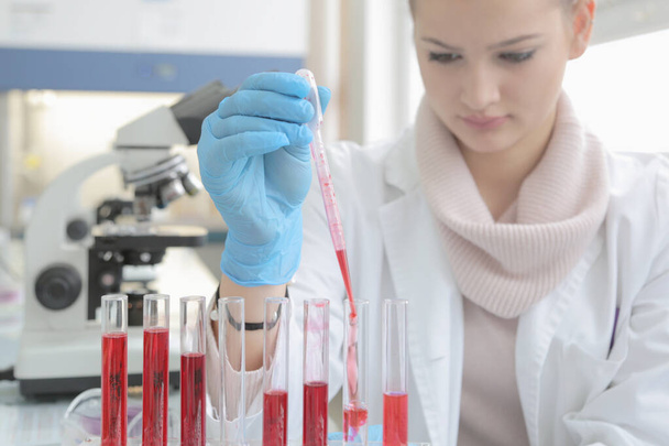 Nuori nainen Laboratorion tiedemies työskentelee laboratoriossa koeputkien kanssa - Valokuva, kuva