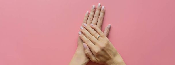 Stylish trendy female pink manicure. Beautiful young woman hands on pink pastel background with place for text. Horizontal long banner for web design. Minimal creative concept. Flat lay - Photo, Image