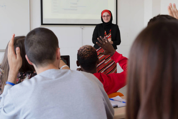 Γυναίκα μουσουλμάνα καθηγητής εξηγήσει μάθημα στους μαθητές και να αλληλεπιδρούν  - Φωτογραφία, εικόνα