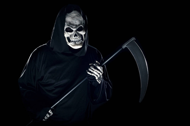 Grim Reaper ghost coming out of the shadows with a scythe or sickle.  The scary demon or monster depicts Halloween and Day of the Dead holiday. - Photo, image