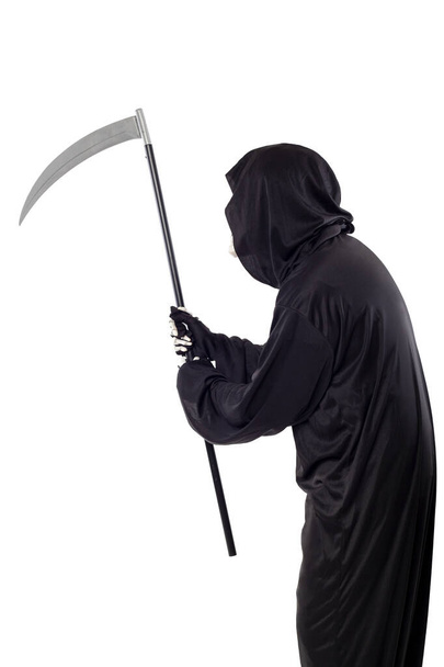 Chmurný smrťák nebo smrtelný halloweenský kostým izolovaný na bílém pozadí. Kostlivec má na sobě černý plášť s kapucí. Boční pohled v profilu pro kompozity. - Fotografie, Obrázek