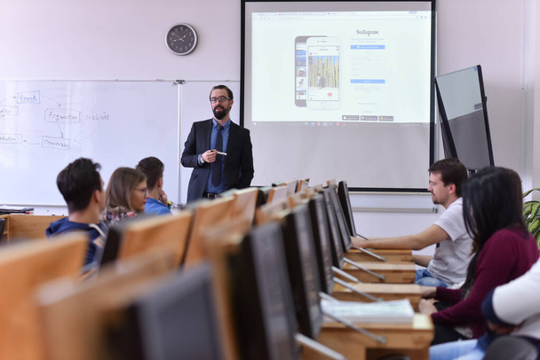Профессор-мужчина объясняет урок студентам и взаимодействует с ними - Фото, изображение