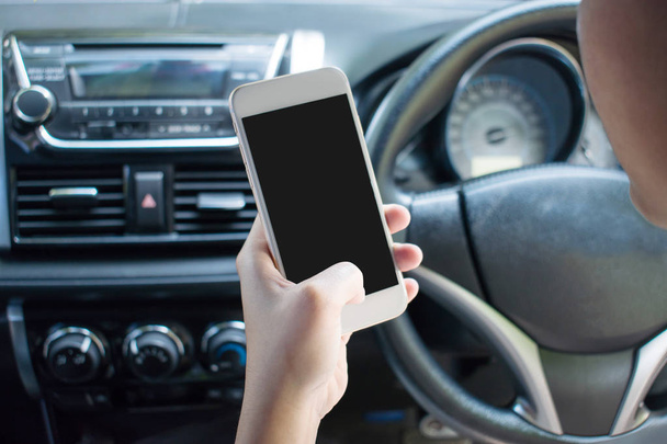 Immagine ravvicinata di una mano che utilizza uno smartphone su un'auto durante la guida
 - Foto, immagini