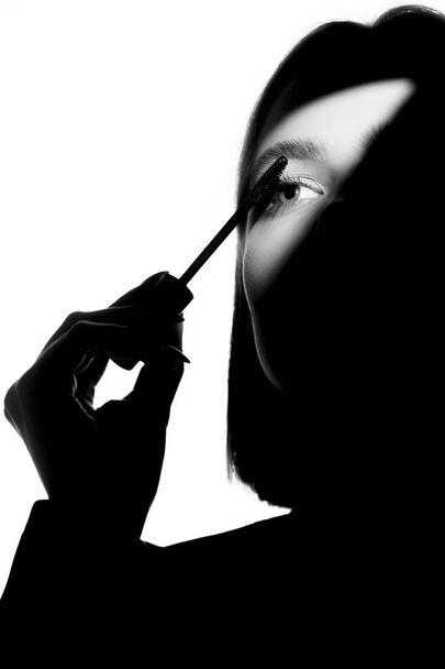 Epic promotional portrait of a girl with applicator and mascara brush. Black and white minimalistic advertising concept. - Valokuva, kuva