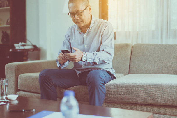 Senior asian man having rest and using smartphone connecting internet at home,Relaxing time,Happy and smiling - Foto, Imagen