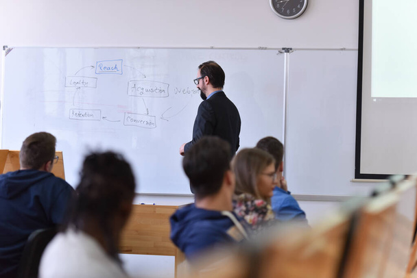 Profesor masculino explicar lección a los estudiantes e interactuar con ellos - Foto, imagen
