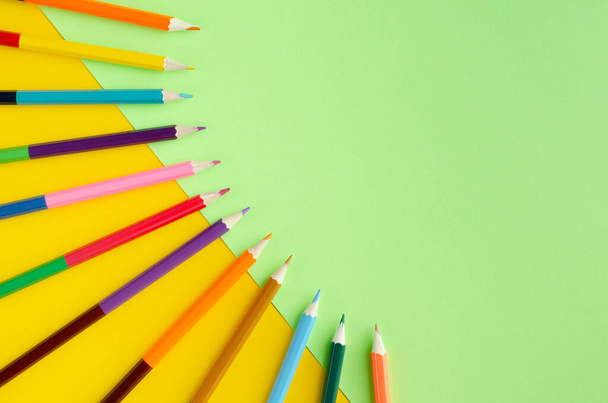 Colored pencils composition on yellow and green background. - Photo, image