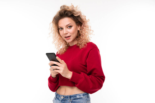 nuori nainen poseeraa matkapuhelimen kanssa valkoista taustaa vasten
   - Valokuva, kuva