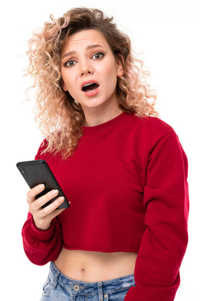 młoda kobieta pozowanie z telefonu komórkowego na białym tle   - Zdjęcie, obraz