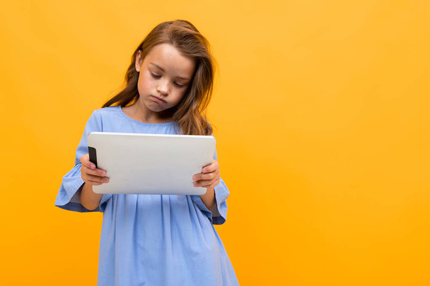 linda niña con la tableta posando sobre fondo naranja
  - Foto, imagen
