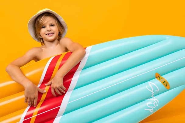 cute little boy with inflatable mattress against orange  - Fotó, kép