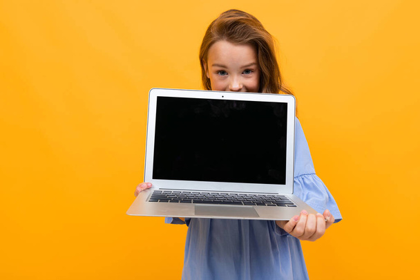 cute little girl z laptopem na pomarańczowym tle  - Zdjęcie, obraz
