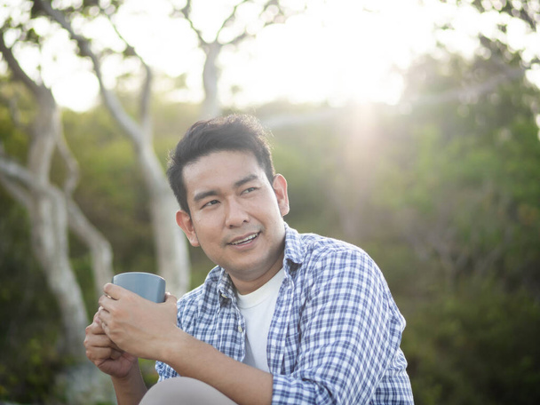Asian man holding coffee cup with nature outdoor, lifestyle conc - 写真・画像