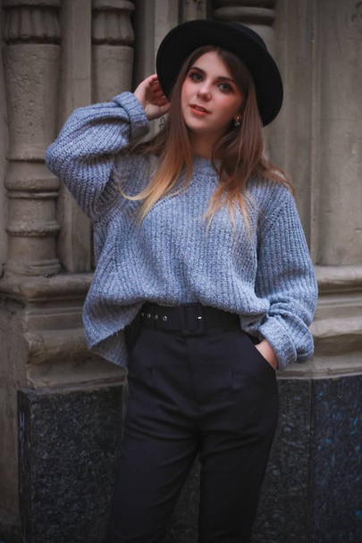 Stylish autumn girl  in the center of the old town. Sweater, hat - Photo, image