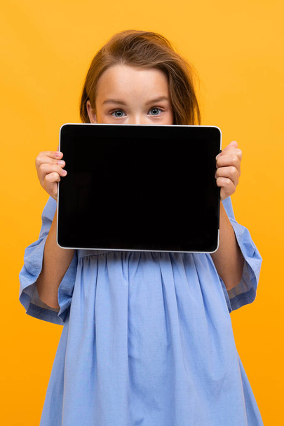 χαριτωμένο κοριτσάκι με tablet θέτει σε πορτοκαλί φόντο  - Φωτογραφία, εικόνα