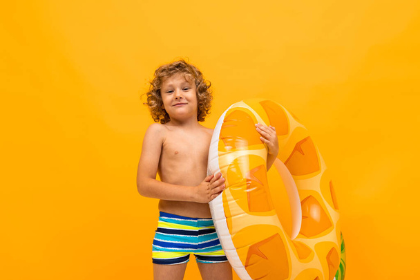 lindo niño pequeño con anillo de goma contra fondo naranja
  - Foto, imagen