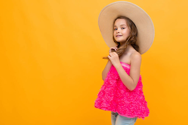 beautiful emotional little girl in straw hat posing against orange background  - Foto, afbeelding