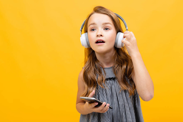 cute little girl listening to music posing against orange background - Fotoğraf, Görsel