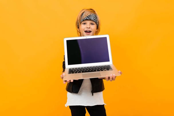 Portakala karşı poz veren dizüstü bilgisayarlı çocuk  - Fotoğraf, Görsel