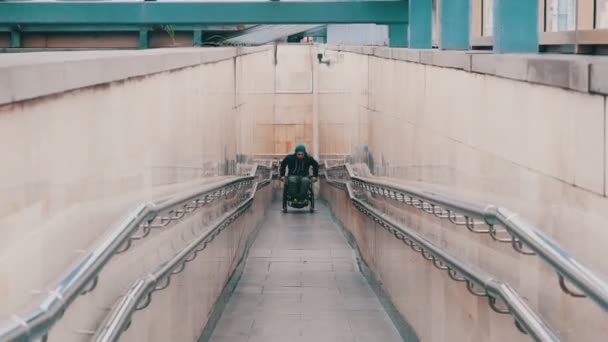 Niepełnosprawny mężczyzna na wózku inwalidzkim wstaje z wysiłkiem na długiej rampie - Materiał filmowy, wideo