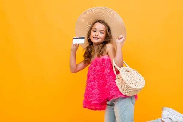 klein meisje als dame poseren met credit card tegen oranje achtergrond  - Foto, afbeelding