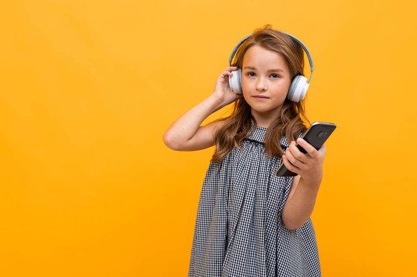 cute little girl listening to music posing against orange background - Φωτογραφία, εικόνα