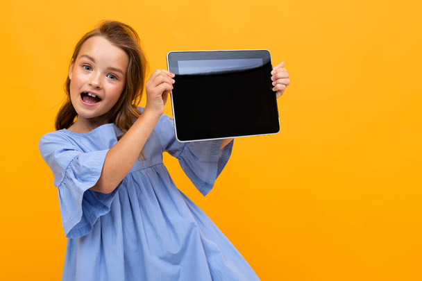 cute little girl with tablet posing against orange background  - Φωτογραφία, εικόνα