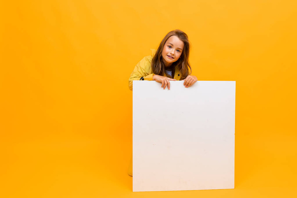 κοριτσάκι με λευκό πίνακα σε πορτοκαλί φόντο  - Φωτογραφία, εικόνα
