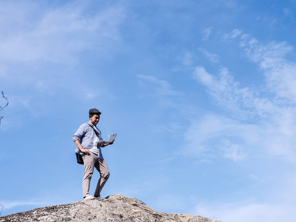 Touriste asiatique debout sur le rocher et regarder carte avec ciel bleu
 - Photo, image