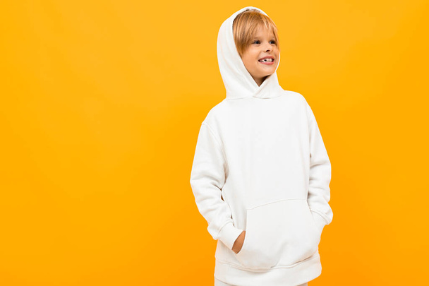emotional boy in white hoodie posing against orange background - Фото, изображение
