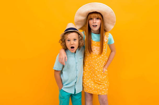 cute boy and girl posing against orange background  - Фото, изображение