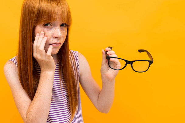 girl with bad vision against orange background  - Фото, изображение