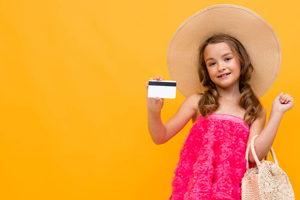 pieni tyttö kuin nainen poseeraa luottokortin kanssa oranssia taustaa vasten
  - Valokuva, kuva