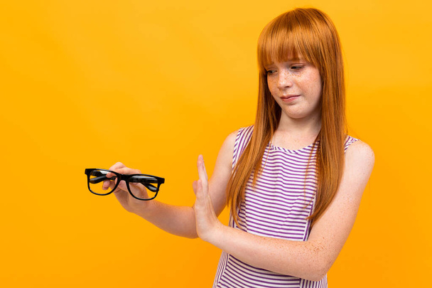 girl with bad vision against orange background  - Φωτογραφία, εικόνα