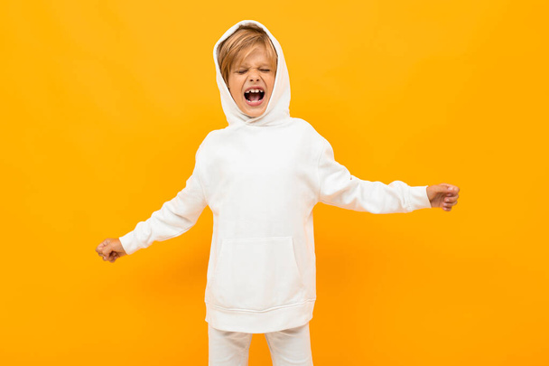 chico emocional con capucha blanca posando sobre fondo naranja
 - Foto, Imagen