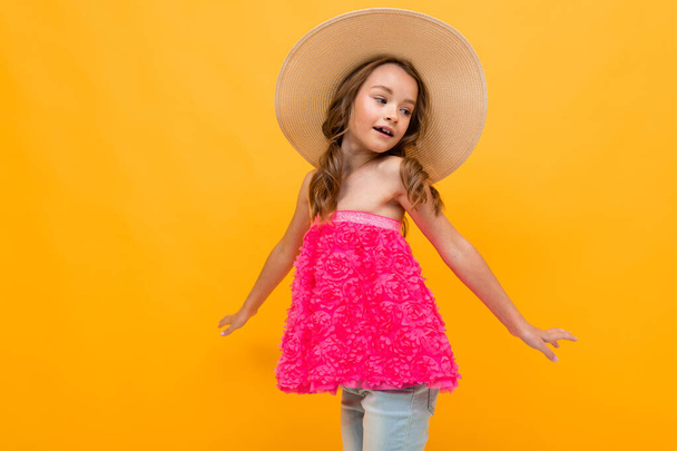 beautiful emotional little girl in straw hat posing against orange background  - Φωτογραφία, εικόνα