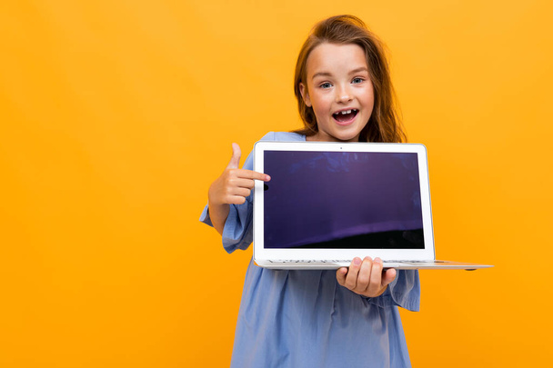 милая маленькая девочка с ноутбуком на оранжевом фоне
  - Фото, изображение