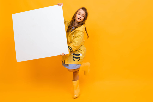 klein meisje met wit bord tegen oranje achtergrond  - Foto, afbeelding